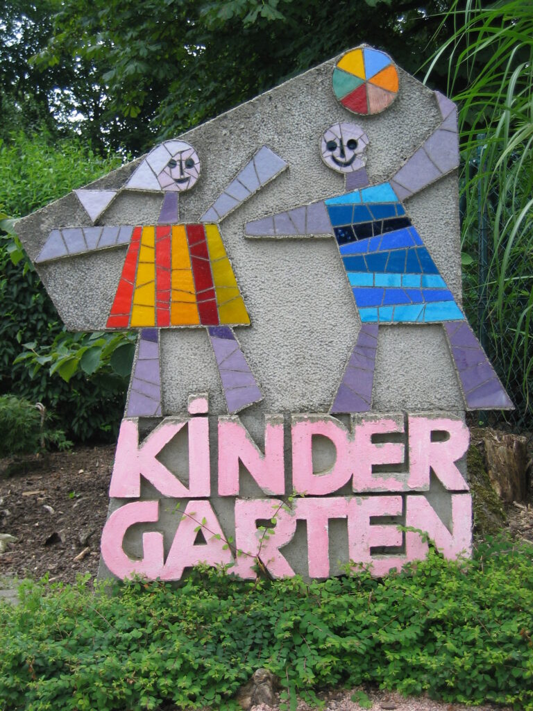Foto eines gestalteten Steins mit Mosaik zweier spielender Kinder und dem Schriftzug Kindergarten